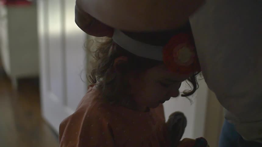 A woman adjusting a headband on a little girl's head