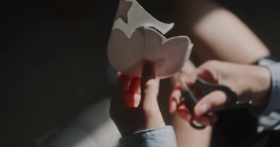 Pregnant woman with black shorts and blue shirt cuts decorations with scissors