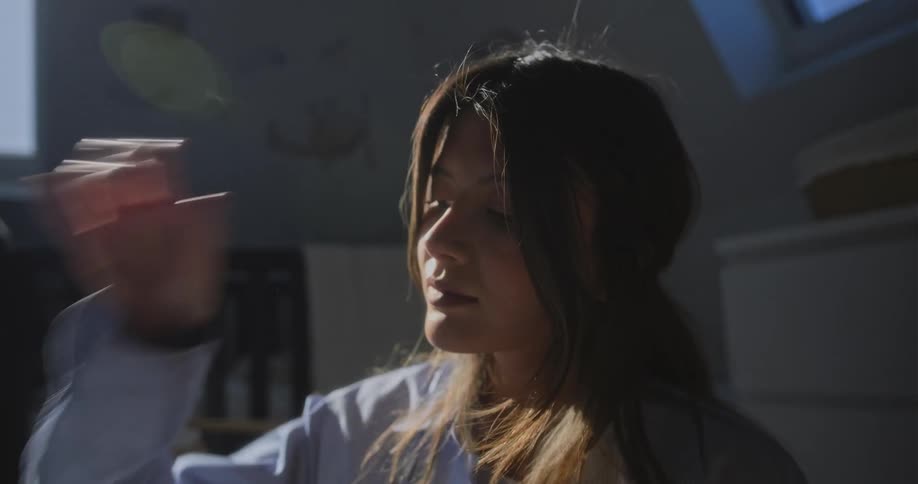 A woman is sitting indoors and looking at an object