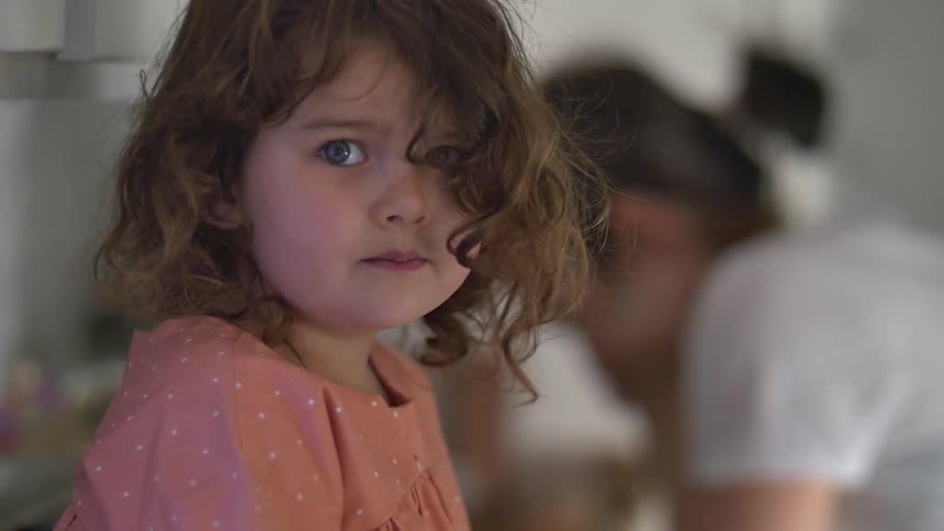A girl looks worried with a woman behind her