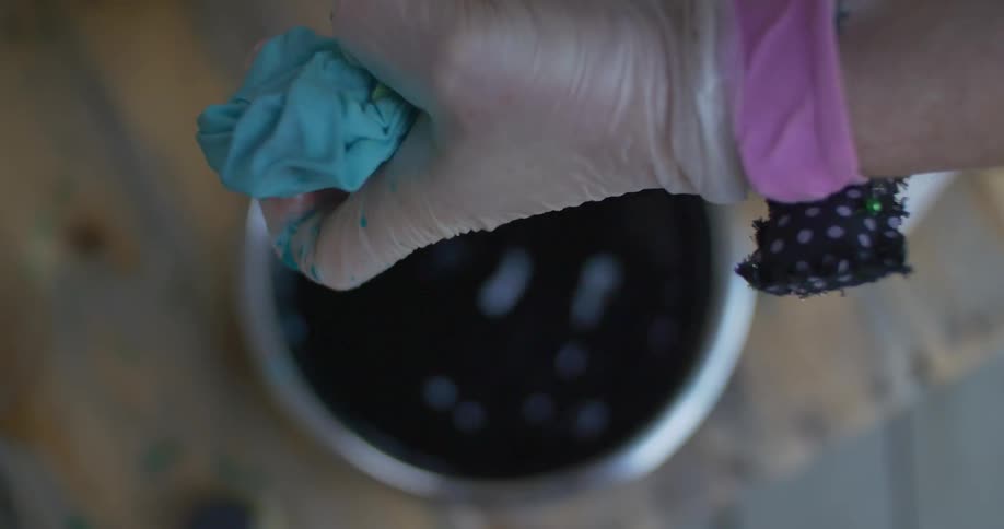 A person is wringing liquid from cloth into a bowl below