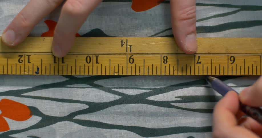 A person traces with a ruler on fabric
