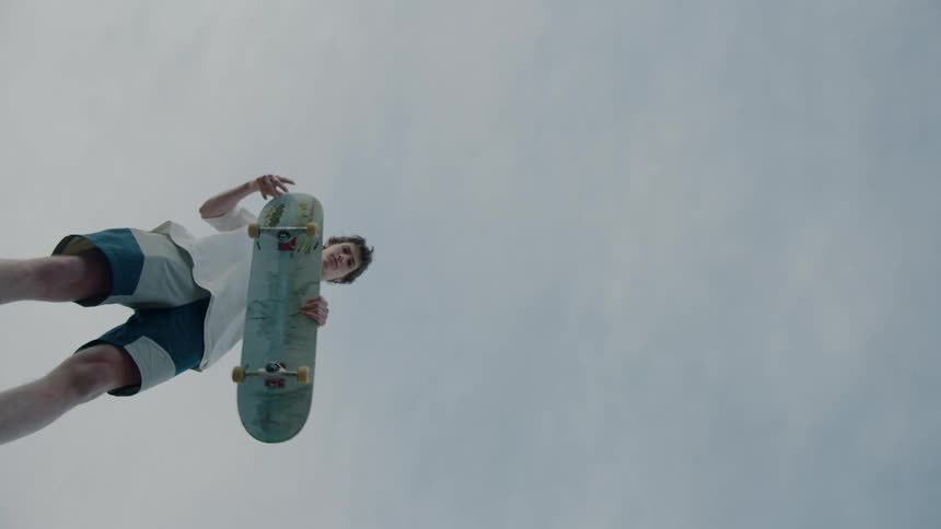 A teenager is holding a skateboard outdoors