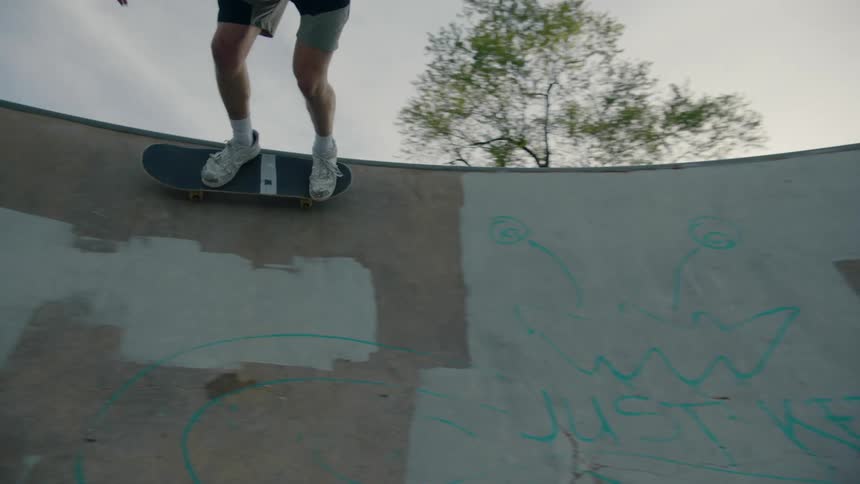 A teenage boy is riding his skateboard on concrete walls in a skateboard park