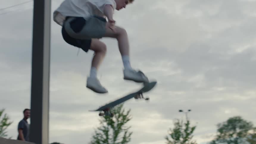 Teenage boy jumps on skateboard in parking lot outside