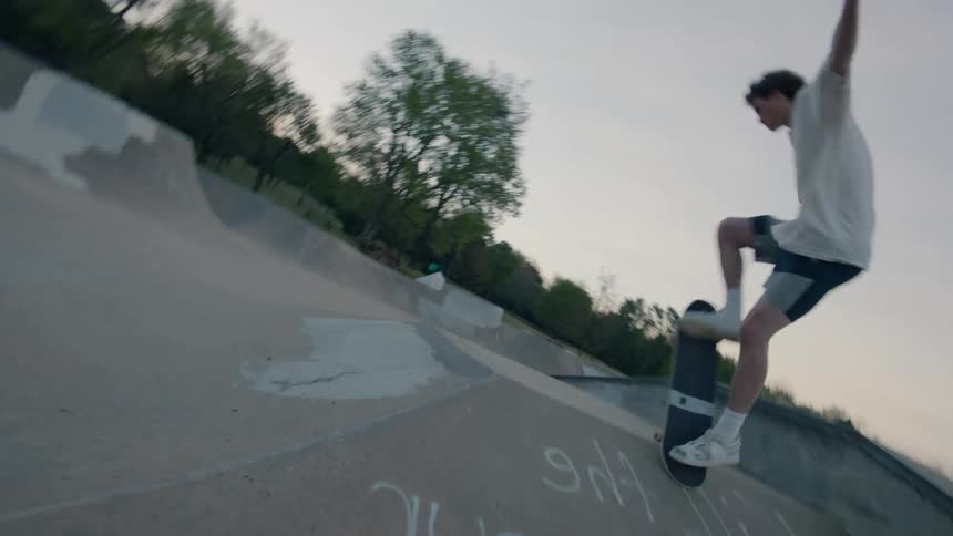 Teenager riding a skateboard on an empty skate park on a small town at evening