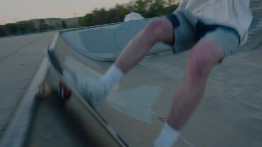 Teenager riding a skateboard on an empty skate park on a small town at evening