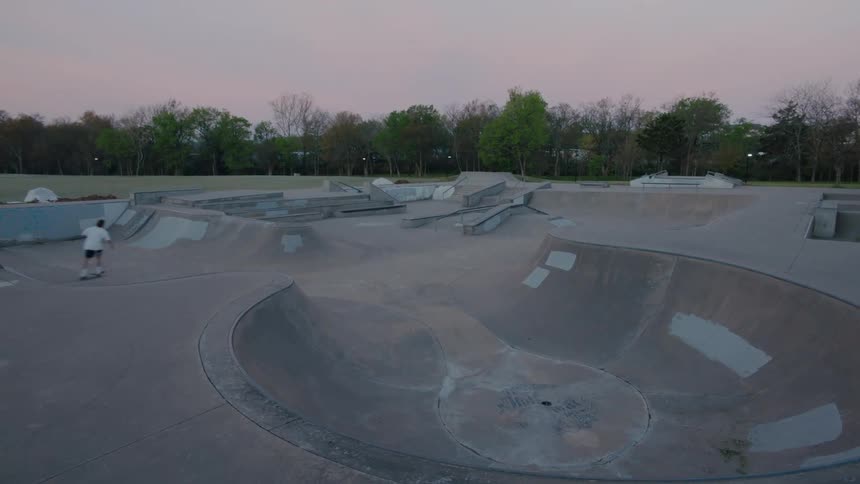 Skateboarder riding across bowls at skatepark on a cloudy day