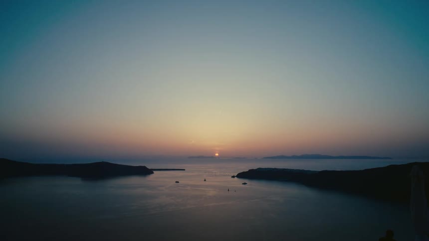 The sun is setting in the horizon over the beach