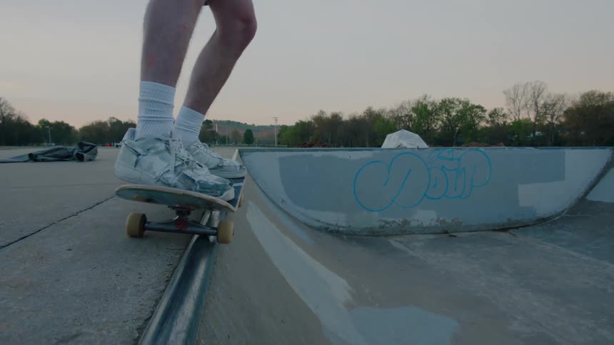 Male skateboarder skating on edge of bowl at a skatepark