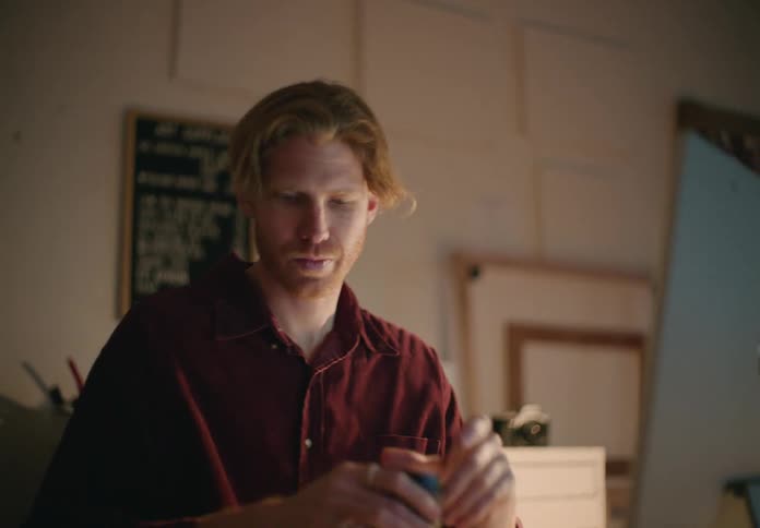 Young blonde man shopping for photography camera parts on a computer at home