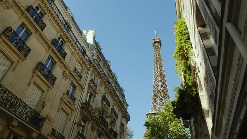 Eiffel tower in paris against a blue sky seen from one of the surrounding streets