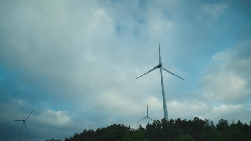 Silhouette of a wind turbine slowly turning against a blue sky at evening