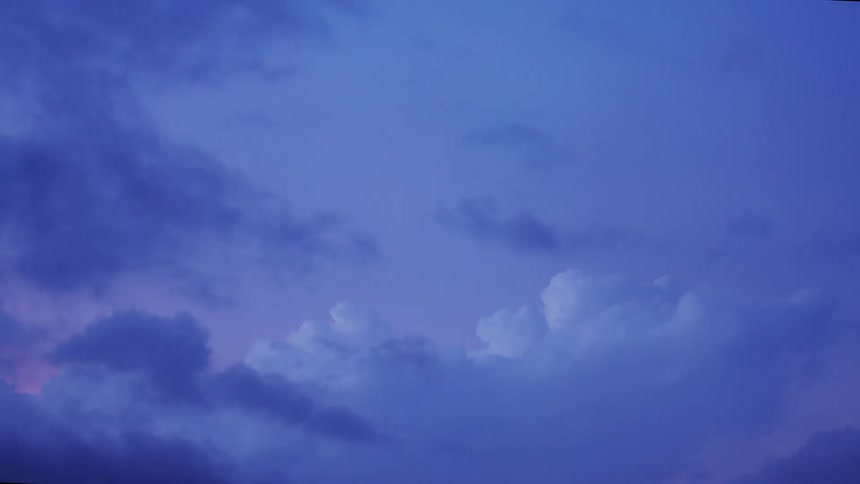 Time Lapse of beautiful blue hour ethereal cumulus clouds are in a pink sky and darker clouds move in across the sky