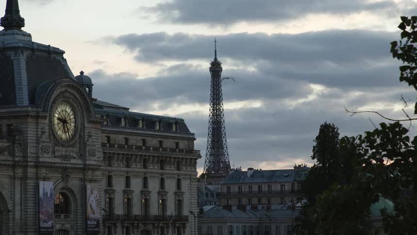 Beneath a cloudy sky a world famous landmark stands tall above the nearby buildings