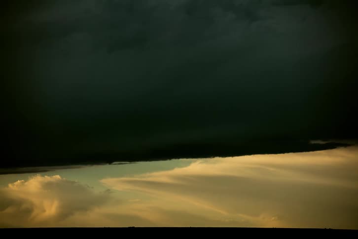 Time lapse of a massive anvil cloud building far away on the horizon at sunset