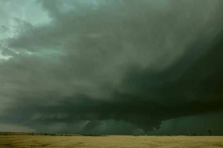 A time lapse shows dark supercell storm clouds pass overhead above a grassy field in the midwest USA