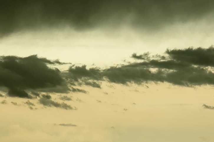 Time lapse of moving dark clouds at sunset against a glowing peach colored sky