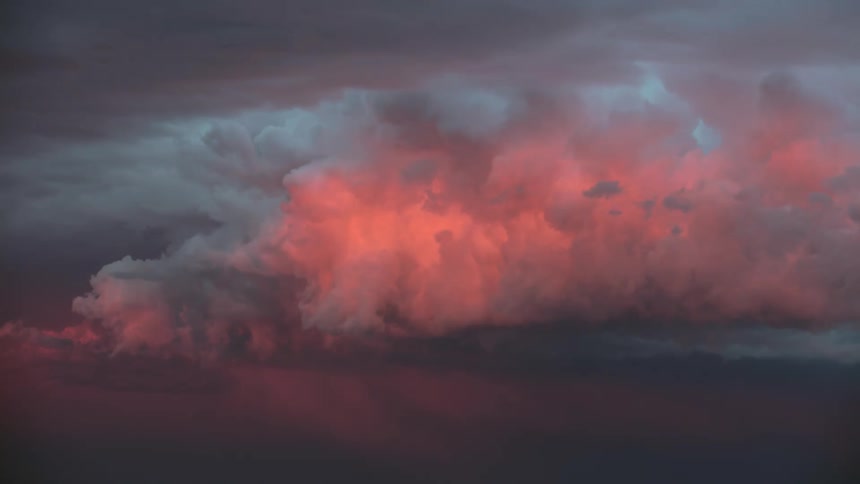 Lightning and beautiful sunset storm clouds roil on the horizon as the sun sets and the day ends