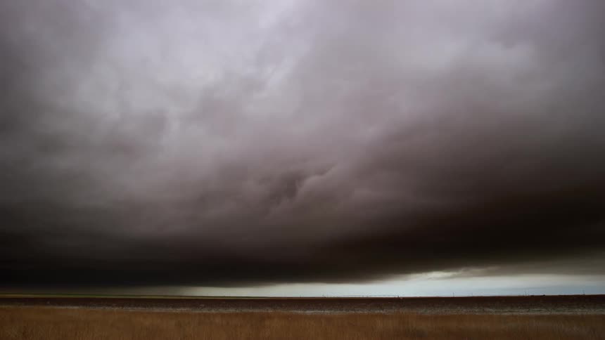 Time lapse of a thick layer of moving clouds changing colors obscuring the sky over the plains