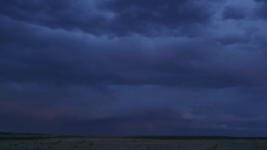 Time lapse of dark super cell clouds and lightning flashing as the storm rolls into the far horizon