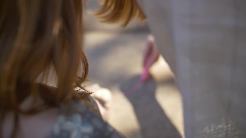 A woman draws in chalk on the ground as another watches
