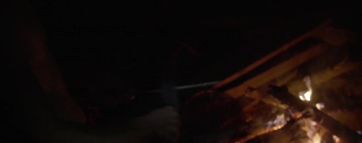 A person is sharpening their blade by a fire