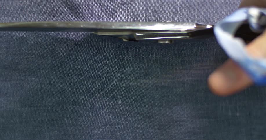 A person uses shears to cut fabric