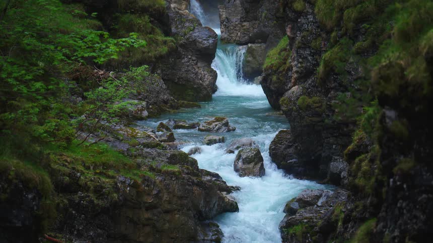 Water flows from a waterfall into a stream and continues on over the rocks
