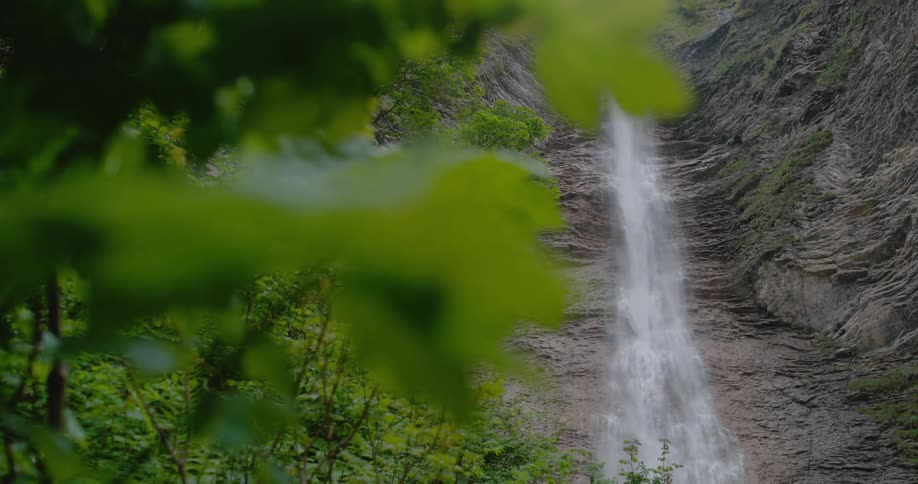 A thin waterfall cascades down the surface of a rocky cliff