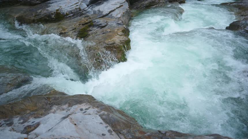 Turbulent river rapids flowing and twisting around the rocks