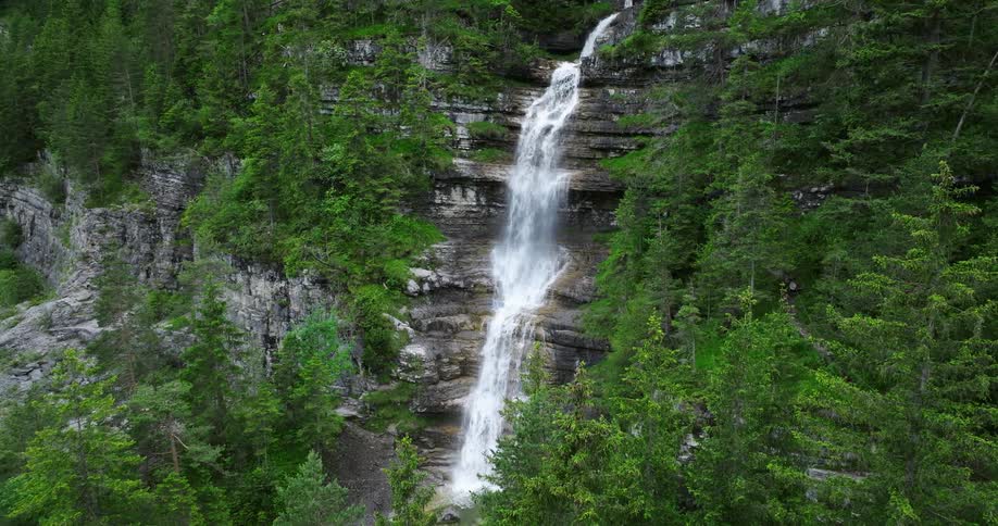 A waterfall rushes down a cliff in the woods