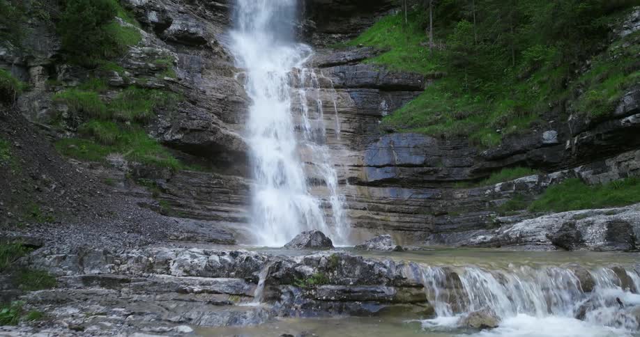 A waterfall rushes down a cliff and into a river