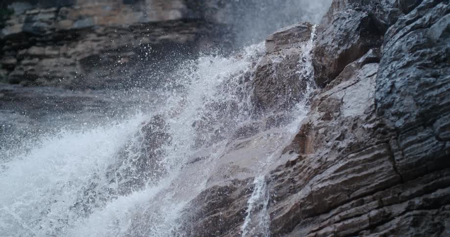 The view is of water that is splashing by a rock outside