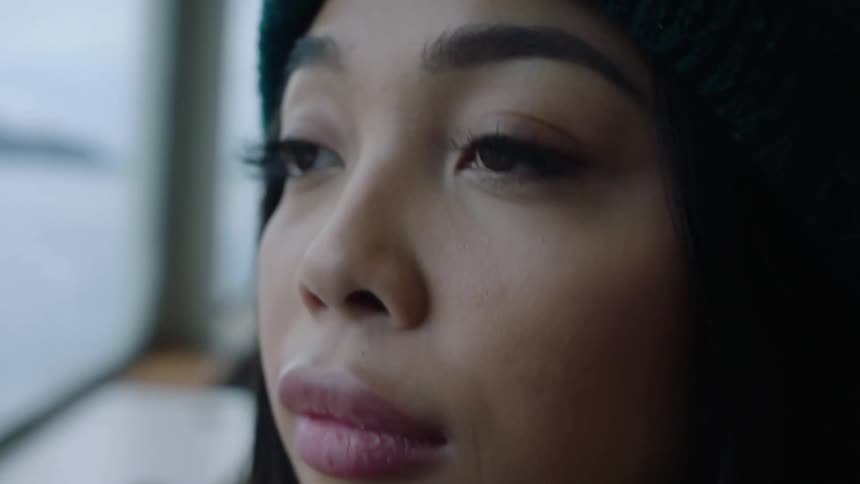 A woman wearing a dark knit cap is standing outside blinking her eyes