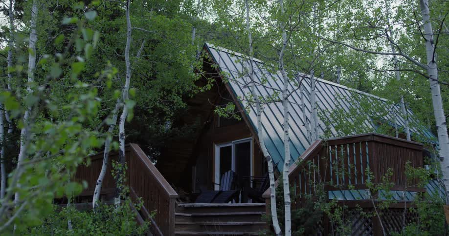 A person turns off the light inside an a frame cabin in the woods