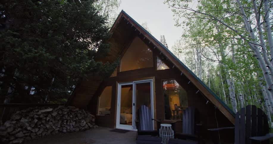 The view is of a cabin in the daytime located in the forest area