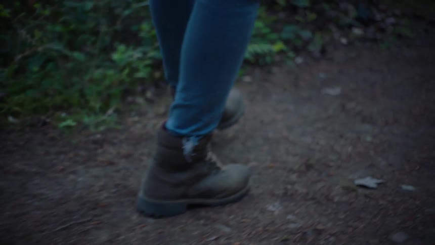 A man hikes down a dirt trail through the woods