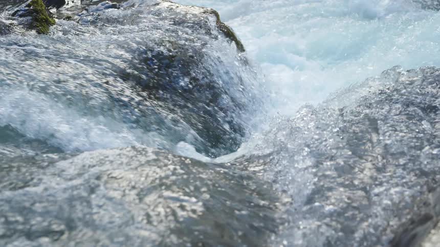 Water in a stream is rolling over rocks as it flows down the rapids