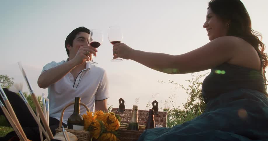A couple is drinking some wine and having a picnic