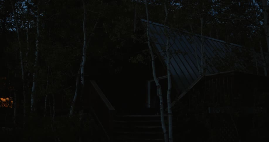 At nighttime there is a cabin located in the forest area