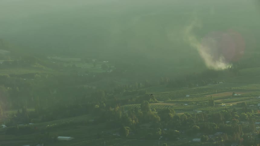 A red biplane is flying in the sky during sunset