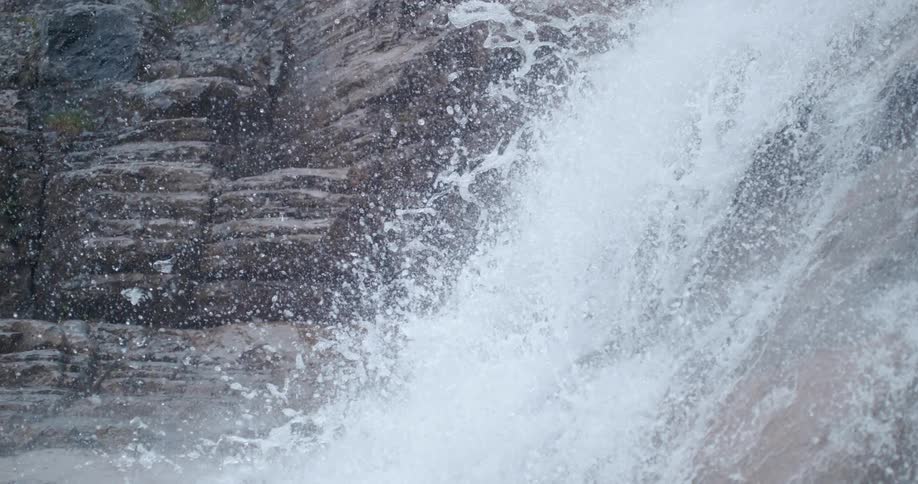 Water splashes as it rolls over the waterfalls over a mountain cliff