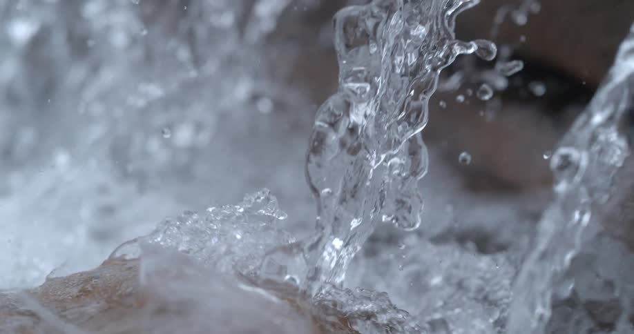 Close up of turbulent water on a river rapids flowing over big rocks at daytime