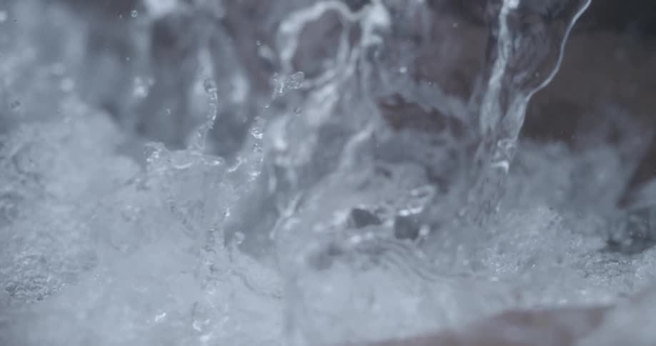 Water from above falls in translucent sheet onto water below creating foam and spray