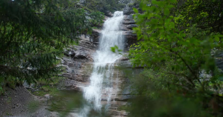 A waterfall rushes down a step style cliff