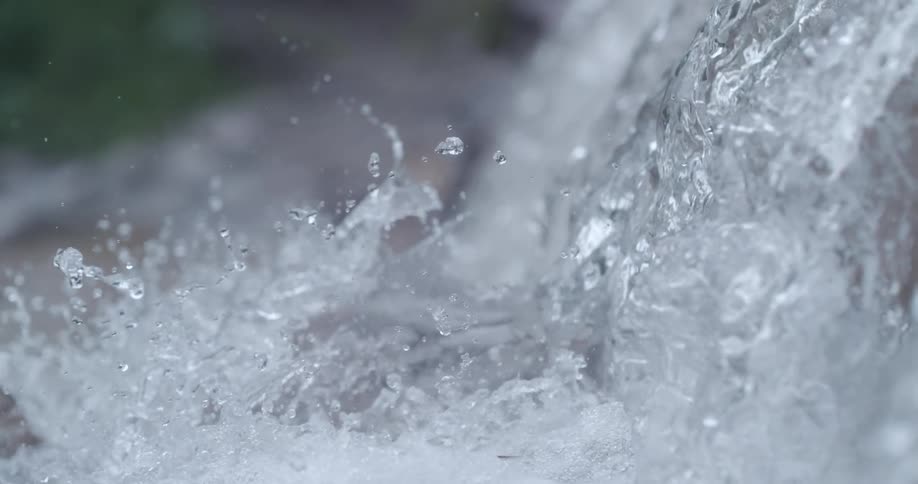 What flows down a drop splashing and foaming with vegetation in the background