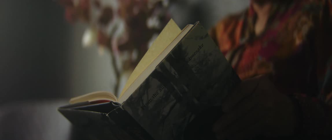 A woman sits and reads a hardcover book