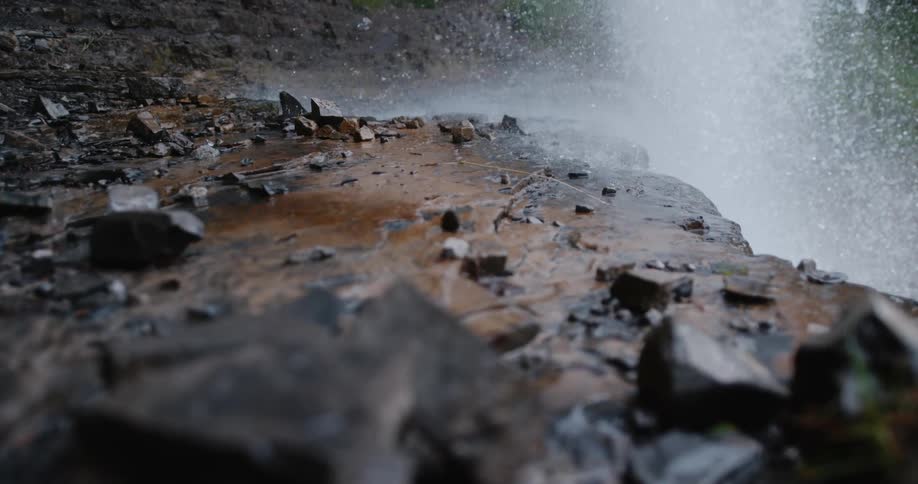 Spray from flowing waterfall wets rock ledge