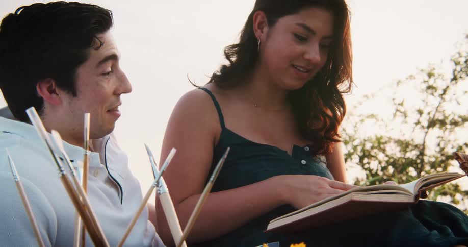 A couple is hanging outside and reading a book